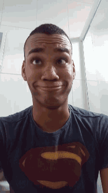 a young man wearing a superman shirt makes a funny face
