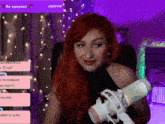 a woman with red hair is sitting in front of a microphone with a purple background and the number 100008 on the bottom