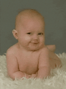 a baby is smiling while laying on a white blanket