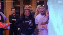 a woman in a black shirt that says " i 'm fine the " holds a glass of wine