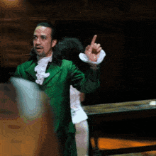 a man in a green suit is pointing up
