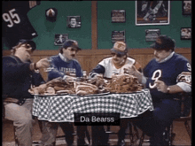 a group of men are sitting around a table with a checkered table cloth and the words da bearss on the table