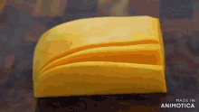 a piece of yellow cheese is sitting on a wooden table with the words made in animatica below it