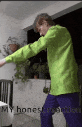 a man in a green shirt and purple pants is dancing in front of a table and chairs .