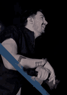 a man with a tattoo on his arm holds a microphone in his hand