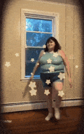 a woman is dancing in front of a window with stars coming out of it