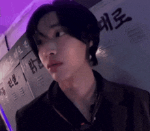 a close up of a person 's face in front of a purple wall with chinese writing on it