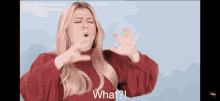 a woman in a red sweater is making a funny face and says " what "
