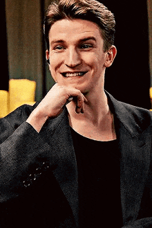a man in a suit is smiling and holding his hand to his chin .