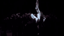 a group of people are standing in a dark room and a person is holding a stick in the air .