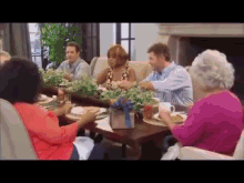 a group of people are sitting at a table eating food