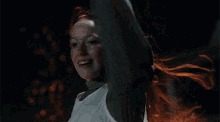 a woman with red hair is smiling with her hands in her hair