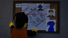 a lego man is standing in front of a bulletin board with pictures and drawings on it