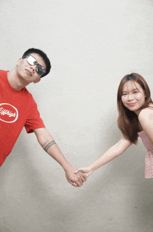 a man and a woman are holding hands and the man is wearing a red shirt that says old high