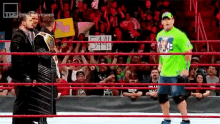 a man in a green shirt stands in a wrestling ring holding a sign that says fame