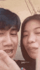 a man and a woman are looking at each other with their eyes closed and smiling .