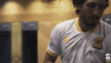 a man in a white shirt with a yellow stripe on the sleeve is running