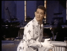 a man in a robe is standing in front of a microphone in a room holding a cup of coffee .