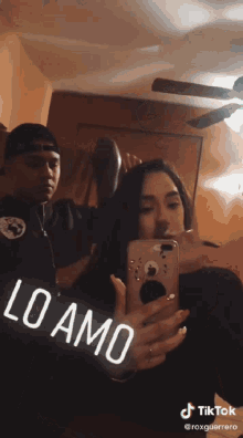 a man is brushing a woman 's hair while she takes a picture of herself in a mirror ..