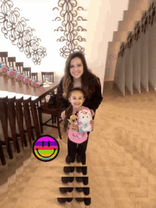 a little girl holding a stuffed animal next to a woman with a smiley face on the floor