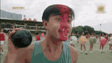 a man with red paint on his face is holding a ball in his hand