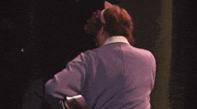 a woman in a purple sweater with a pink bow on her head