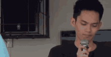 a man is holding a microphone in his hand and looking at the camera .