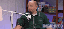 a man in a green shirt is sitting in front of a microphone with the dark web written on the bottom