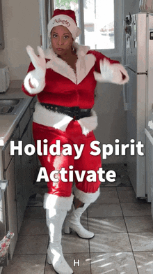 a woman dressed in a santa outfit is dancing in a kitchen with the words holiday spirit activate below her