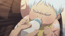 a baby is drinking milk from a bottle with a serious look on his face