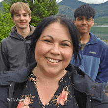 a woman wearing a columbia jacket smiles with two boys in the background