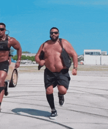 a shirtless man with a bag on his back is running with another shirtless man