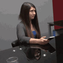 a woman sitting at a table with a cell phone in her hand