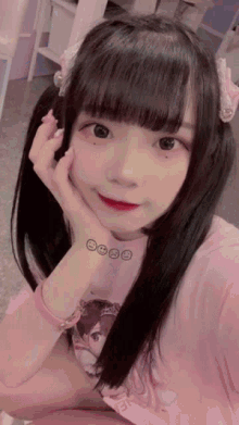 a girl wearing a pink shirt with smiley faces on it taking a selfie