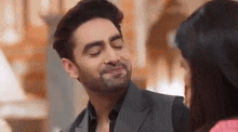 a man in a suit is making a funny face while a woman looks on .
