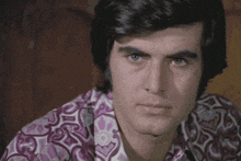 a close up of a man 's face wearing a purple and white shirt