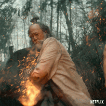 a man with a beard is standing in front of a fire with the word netflix on the bottom