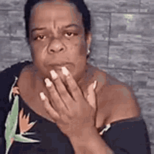a woman is covering her mouth with her hands and looking at the camera .