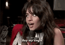 a woman is talking into a microphone and says buy my single