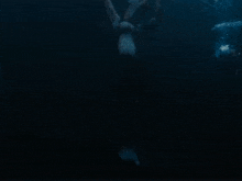 a person is swimming in the dark with their hands up