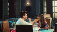 a man is feeding a woman a piece of food while sitting at a table