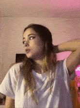 a girl in a white t-shirt is standing in front of a pink wall
