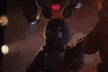 bonnie the bunny is holding a guitar in a dark room .