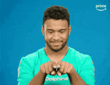 a man in a dolphins jersey points at the camera with the word concussion behind him