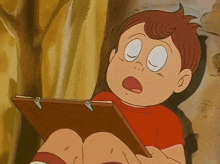 a boy in a red shirt is holding a piece of paper