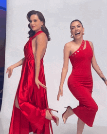a woman in a red dress is standing next to another woman