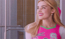 a woman in a pink cheerleading uniform is smiling and looking to the side .