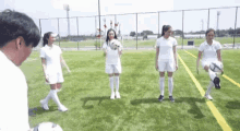a group of female soccer players are standing on a soccer field .