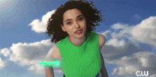 a woman in a green dress is standing in front of a blue sky with the letters cw on the bottom