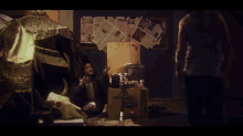 a man is standing in a room with newspapers on the wall and a box that says ' coca-cola ' on it